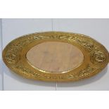 A Glasgow Style Arts & Crafts brass wall mirror, oval, the frame chased with Celtic knot motifs.