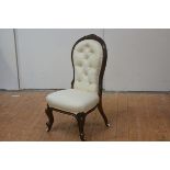 A small walnut framed spoon back nursing chair, mid-19th century, the buttoned back within a moulded