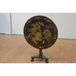 A Chinese gilt-decorated ebonised tilt-top tripod table, the circular top with pagoda and pine