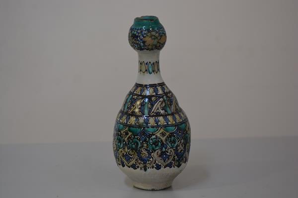A Persian pottery bottle vase of garlic head shape, decorated in a palette of blues and greens in