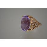 A large amethyst single stone ring, the oval-cut stone claw-set on pierced shoulders and a