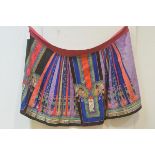 A Chinese woven and embroidered silk pleated skirt, c. 1900, in polychrome panels, embroidered