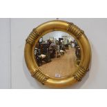 An unusual William IV giltwood mirror, the circular plate within a conforming frame with four ring