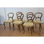 A set of six mid-Victorian walnut drawing room chairs, the balloon backs over serpentine stuffed-