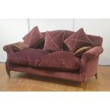 Beaumont and Fletcher, a loose-cushioned sofa, in plum velvet, the camel back over outswept arms, on