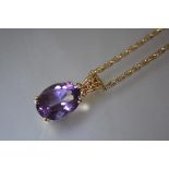 An amethyst pendant, the oval stone claw and scroll set in 9ct gold on a 9ct ropetwist chain.