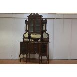 An elaborate Edwardian mirror-backed display cabinet, the superstructure with a swan-neck pediment