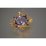 An amethyst brooch, the large oval-cut stone collet-set within a gold wirework band set with four