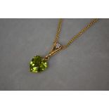 An 18ct gold peridot and diamond pendant, the heart-cut peridot claw-set beneath a bale set with a