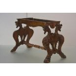 A mid-19th century carved walnut stand (originally a stool), the trestle legs each boldly carved