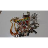 A bag containing miscellaneous costume jewellery inc. a Native American beaded panel, glass bead