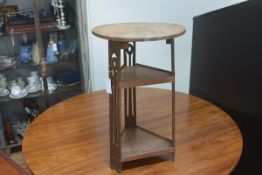 An Edwardian oak circular top two tier occasional table with triangular base and pierced slatted