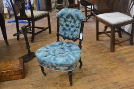 A Victorian ebonised nursing chair with button upholstered back and seat in turquoise damask, on