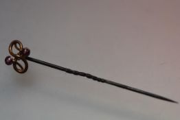 A yellow metal Edwardian figure of eight gem-set stick pin. 5.5cm
