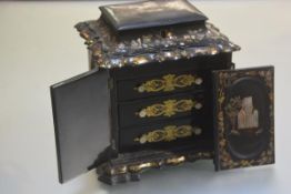 A Victorian papier mache and mother of pearl inlaid sewing cabinet, the hinged top (a/f) enclosing a