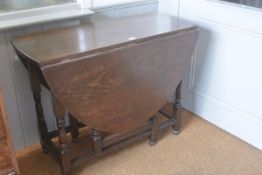 A 1920s oak oval drop leaf gateleg dining table raised on turned baluster supports (h. 74cm x w.