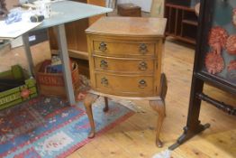 A burr walnut bowfront bedside cabinet, with dummy drawer on carved moulded supports. 72cm by 41cm