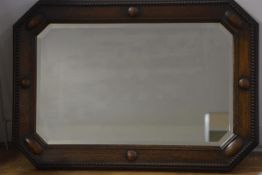 A 1930's oak octagonal wall mirror, with bevelled glass and beaded border. 69cm by 99cm