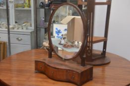 A George III mahogany swing mirror with oval plate, on scroll supports and serpentine inlaid base,