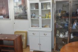 A modern painted two part kitchen cabinet with glazed panel doors to top above two drawers and two