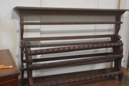 An Edwardian Arts & Crafts carved three tier walnut wall mounted plate rack, with Celtic style snake