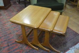 A light elm nest of three Ercol coffee tables raised on shaped end supports and splay feet (tallest: