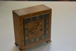 An Art Deco walnut square clock with arabic numerals and twin key apertures, raised on bracket feet,