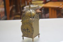 A reproduction 1920s/30s brass lantern style clock with bell and finial surmount, with pierced brass