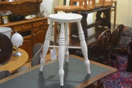 A 19thc stool with circular concave seat, raised on ring turned splay supports united by cross