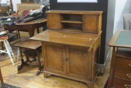 A figured walnut side cabinet fitted two open shelves flanked by panel doors, with fold down top