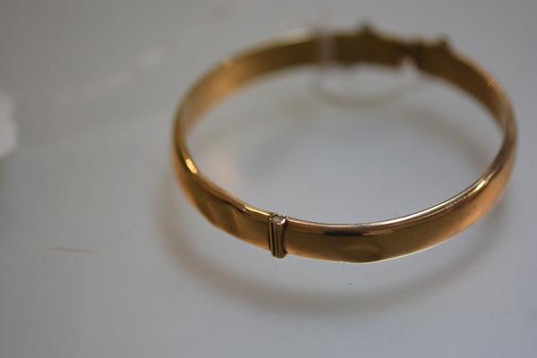 A 9ct gold stiff hinged hollow filled bangle complete with safety chain (a/f) (10.9g)