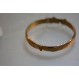 A 9ct gold stiff hinged hollow filled bangle complete with safety chain (a/f) (10.9g)