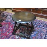 An Ercol oak circular topped occasional table, raised on turned splay supports with relief carved