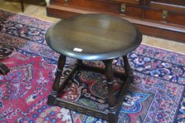 An Ercol oak circular topped occasional table, raised on turned splay supports with relief carved