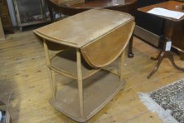 An Ercol light elm three tier drop leaf trolley with moulded edge to each tier, on turned tapered