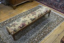 A Victorian walnut fender stool, the rectangular top with faded linen floral pattern upholstery