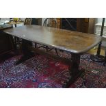 An Ercol dark oak rectangular trencher style dining table with moulded edge, raised on shaped