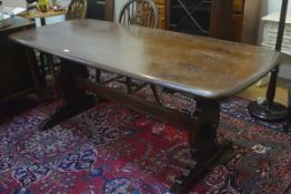 An Ercol dark oak rectangular trencher style dining table with moulded edge, raised on shaped