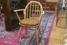 An Ercol low back spindle back open armchair with shaped wood seat on splay tapered supports,