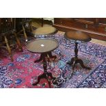 A pair of mahogany oval shaped top occasional tables raised on turned column and tripod support