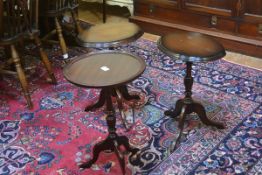 A pair of mahogany oval shaped top occasional tables raised on turned column and tripod support