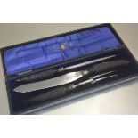 An Edwardian three piece horn handled carving set complete with steel, knife and fork, in original