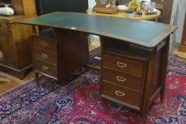 A 1950s walnut crescent shaped twin pedestal desk, the shaped top with inset green leather skiver
