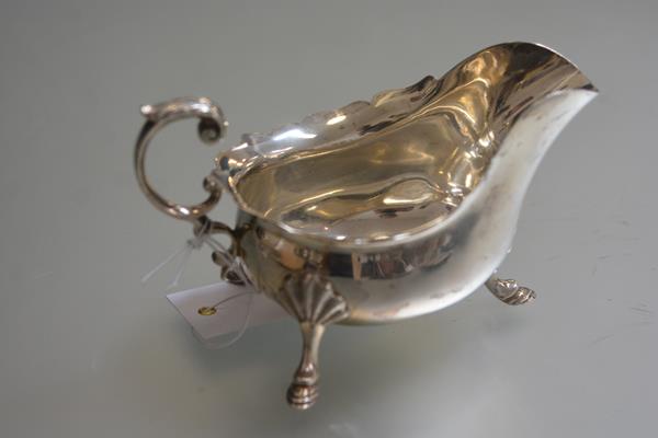 A Sheffield silver George III style scalloped sauceboat by Walker & Hall, raised on shell cast pad