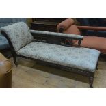 An Edwardian walnut chaise longue with scroll end and baluster support backrest, upholstered in