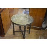 An Eastern brass circular top coffee table with lion mask centre panel enclosed within a foliate and