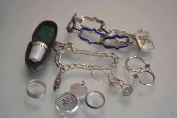 A silver thimble with original case, a white metal blue enamelled bracelet, a silver charm