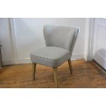 A modern ash framed bedroom chair with curved upholstered back and seat in grey linen fabric, raised