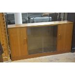 A 1970s teak G Plan bookcase with twin sliding centre panel doors, flanked by panel doors, with