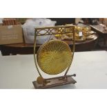 An Edwardian brass dinner gong, raised on pierced curved stand and oak base, complete with felt